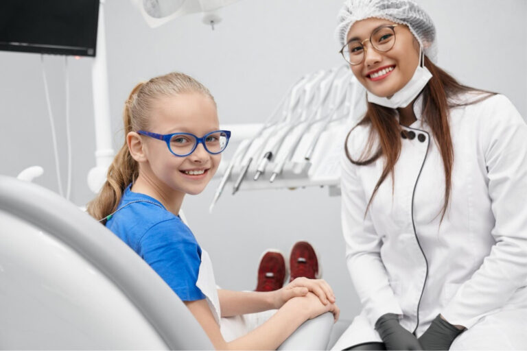 smiling woman and girl in dental office with dental equipment