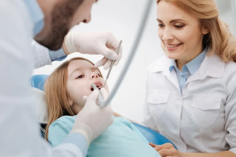 arafed woman with a dentist examining a young girl ' s teeth