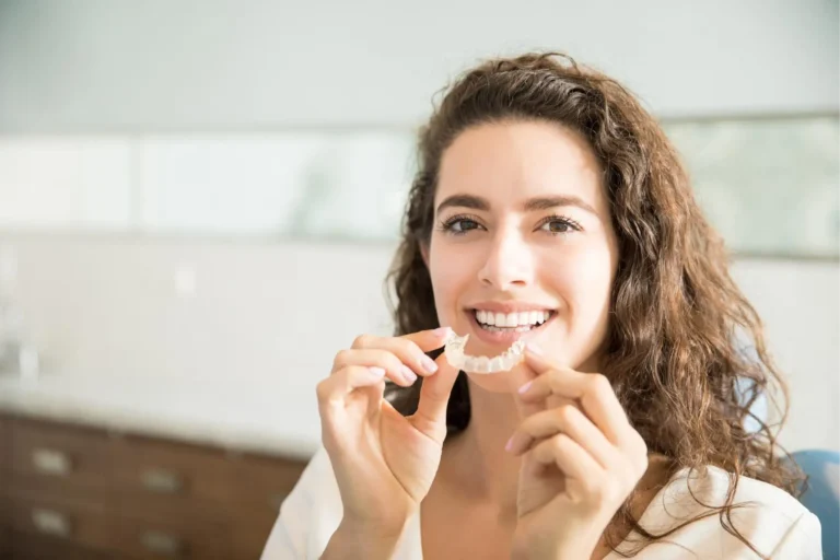 smiling woman brushing teeth with a toothbrush in a bathroom