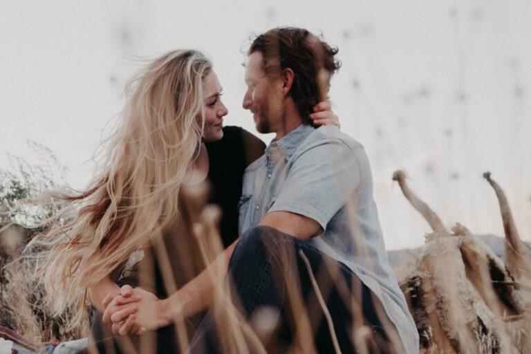 there is a man and woman sitting together in a field