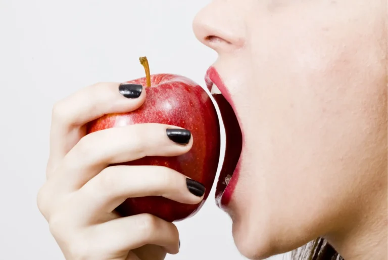 there is a woman eating an apple with a bite out of it