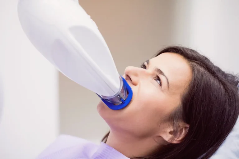 woman in a dentist chair drinking from a bottle with a blue handle