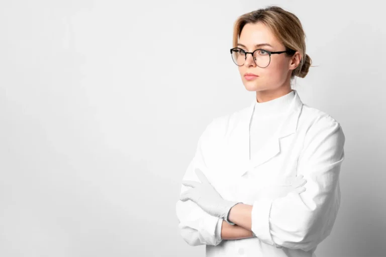 arafed woman in a white coat and glasses standing with her arms crossed