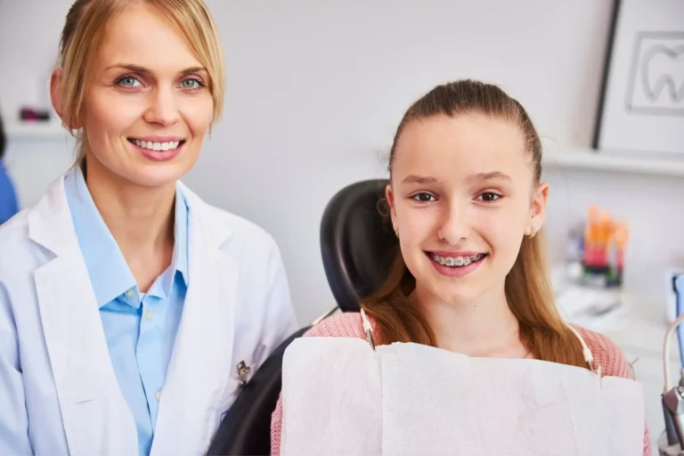 smiling woman sitting in a chair with a girl in a dental chair