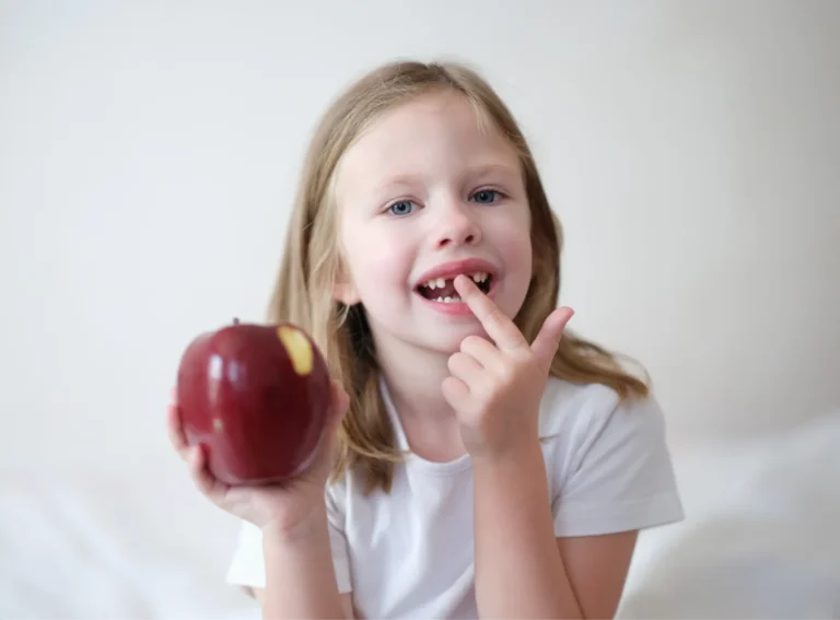 blond girl eating an apple while sitting on a bed