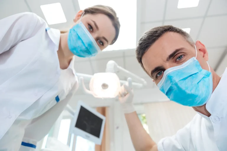 two doctors in masks are standing in a room with a light