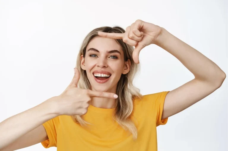 smiling woman in yellow shirt making a gesture with her hands