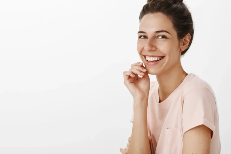 smiling woman in pink shirt holding toothbrush in front of her face