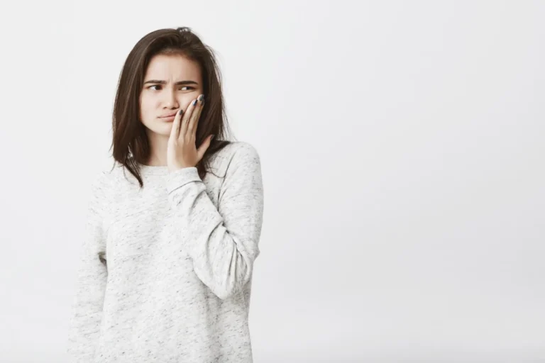 arafed woman in a white sweater covering her mouth with her hands