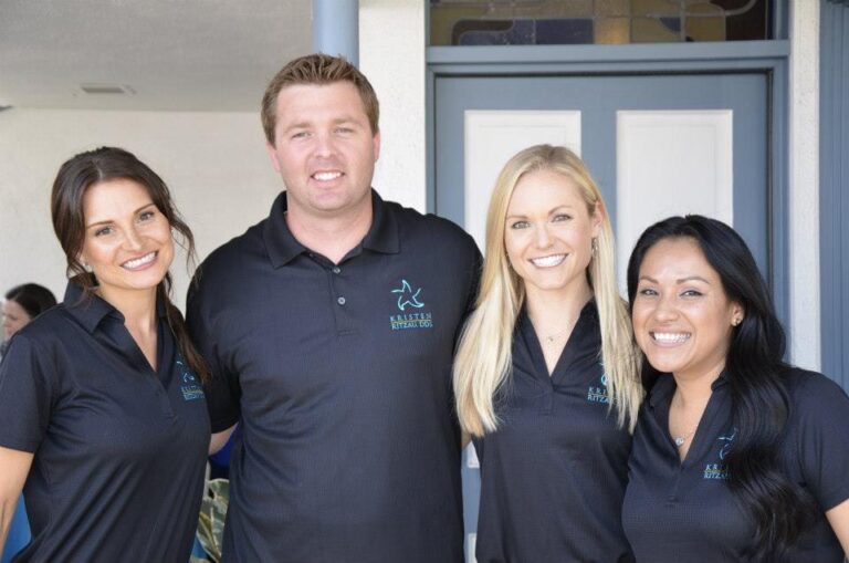 three women and a man are standing in front of a door