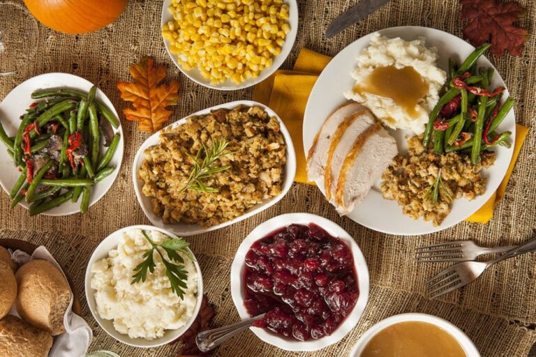 a close up of a table with plates of food and a bowl of gravy