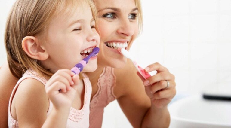 there is a woman and a little girl brushing their teeth