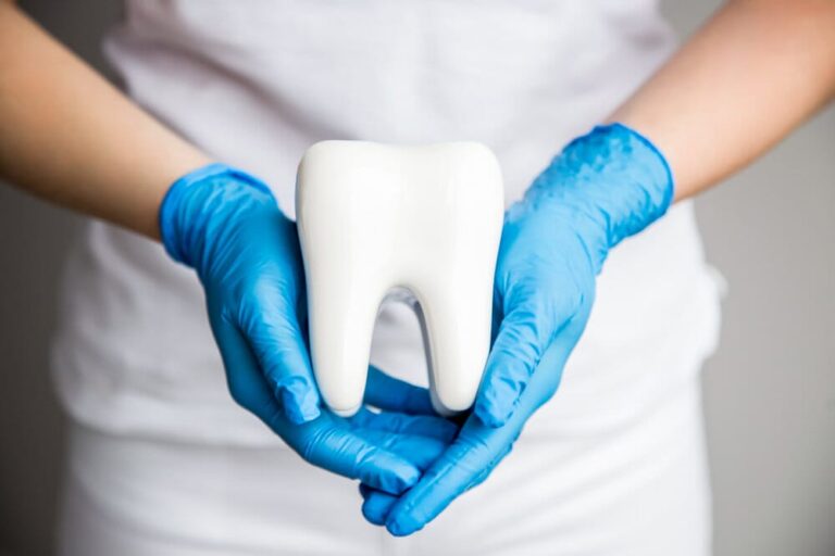 arafed tooth in a blue glove holding a white tooth