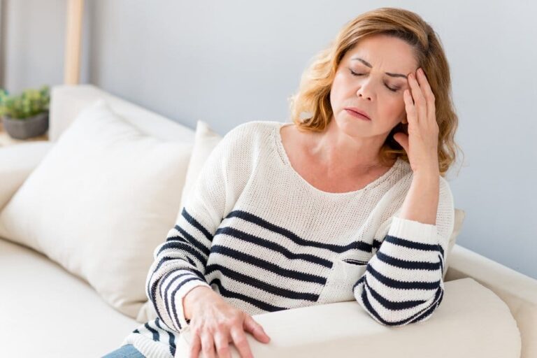 woman sitting on a couch with her hand on her head