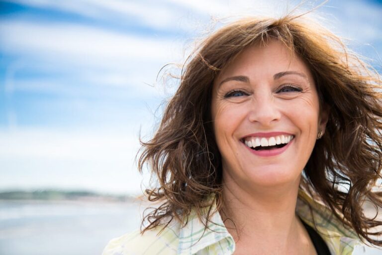 smiling woman with long hair and a green shirt on the beach