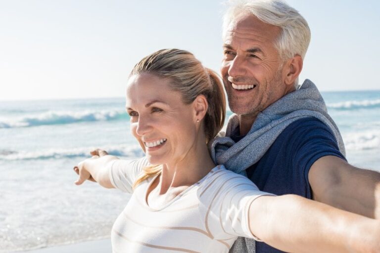 smiling couple taking selfie on beach with ocean in background