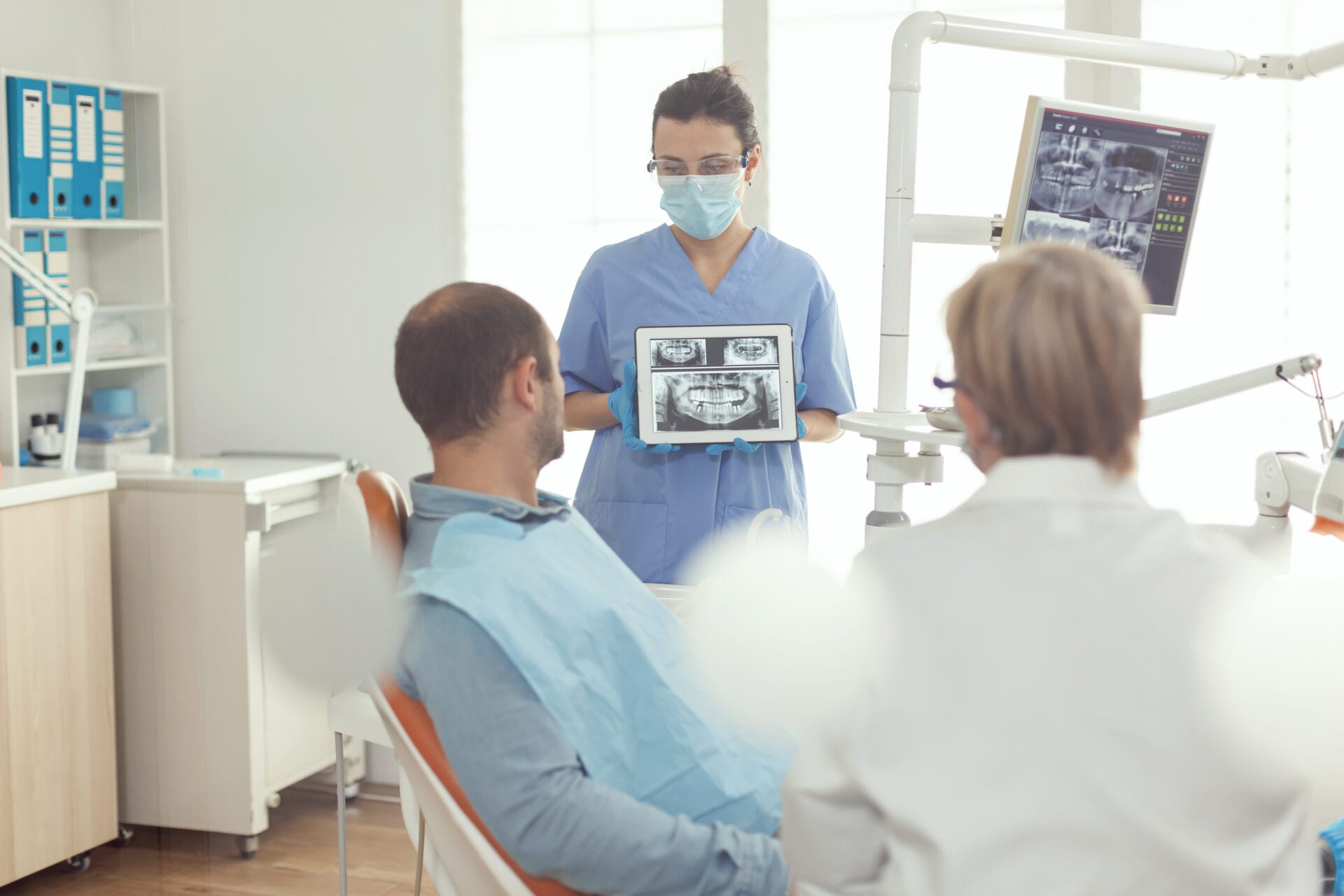 there are two people sitting in a dentist chair with a man in a mask