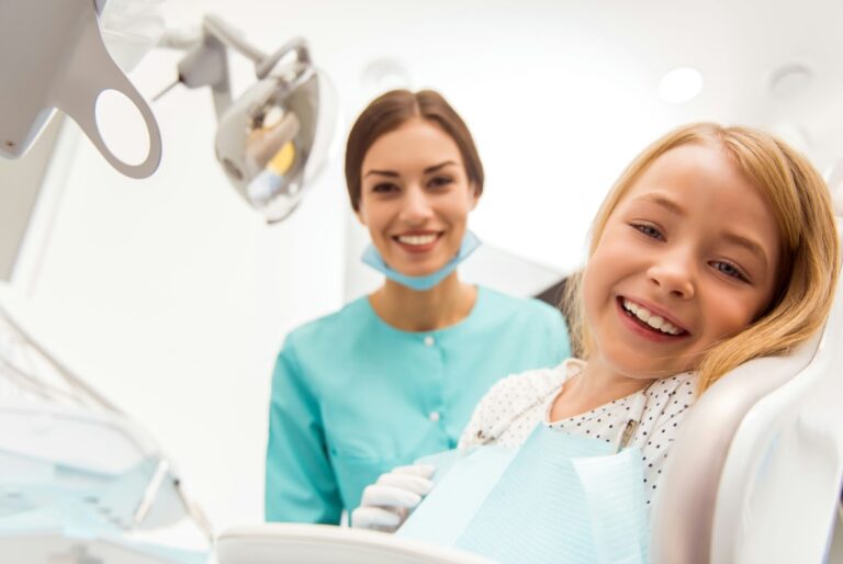 smiling girl sitting in a dental chair with a dentist