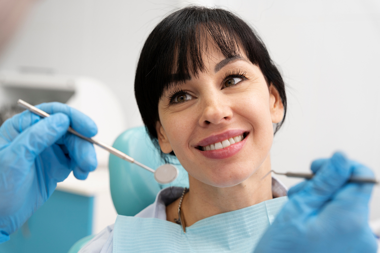 smiling woman in blue gloves holding a pair of scissors in her hand