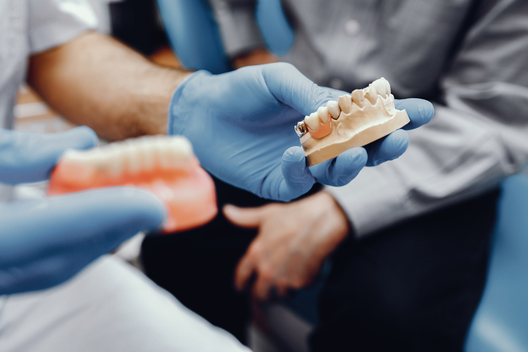 someone is holding a model of a tooth with a dent