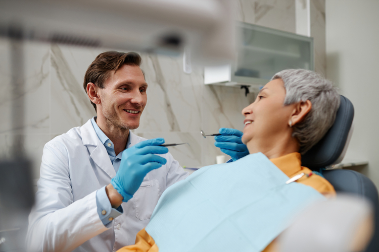 smiling man in a dentist ' s chair with a woman in a chair