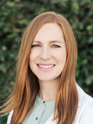 a woman with long red hair and a white lab coat