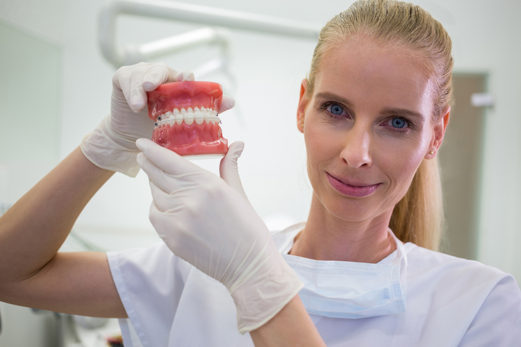 arafed woman in white shirt holding a model of teeth