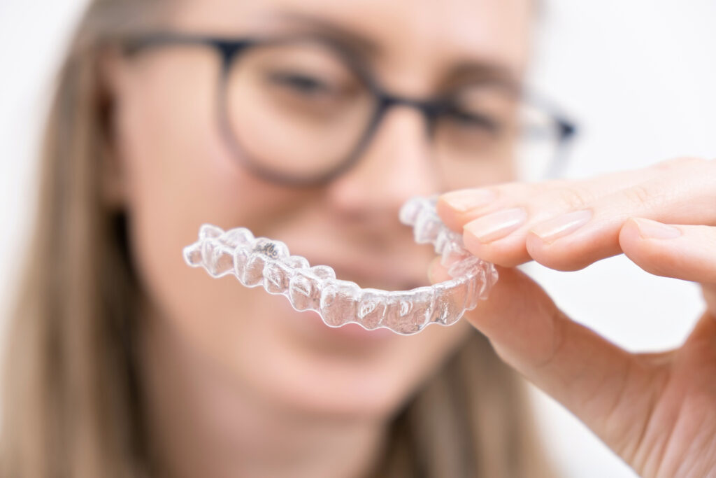 woman holding clear retainer in front of her mouth