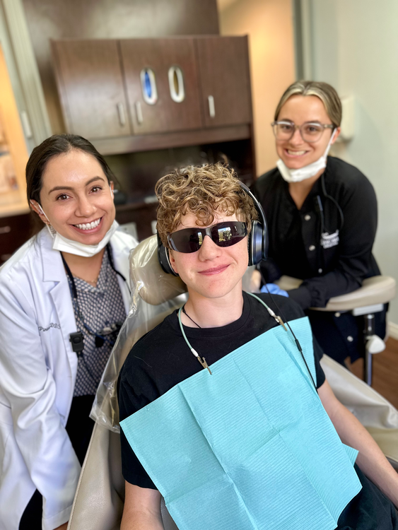 smiling woman in a dental chair with a patient and a dentist