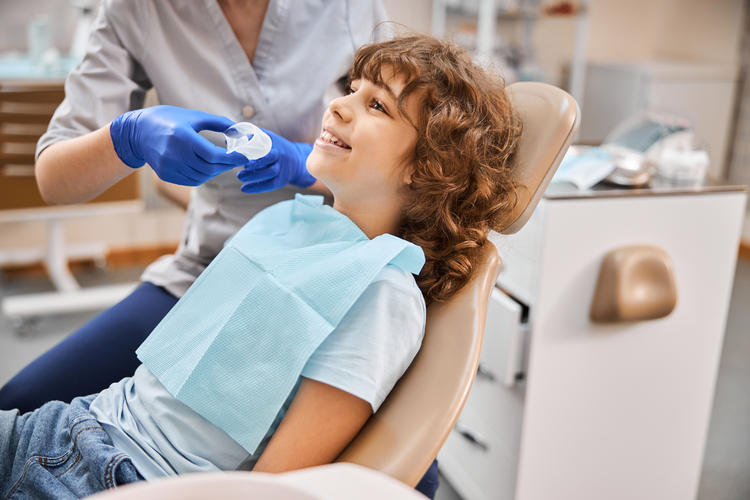 arafed child sitting in a chair with a dentist ' s glove on