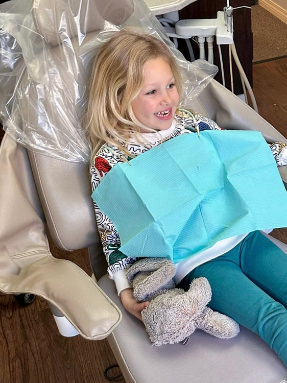 arafed child sitting in a chair with a toothbrush and a blue bag