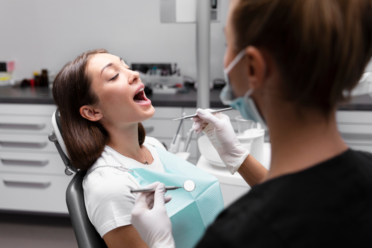 woman in a dentist chair with a toothbrush and a dental instrument