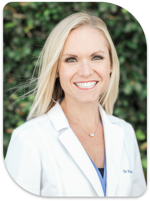 a close up of a woman in a white lab coat smiling