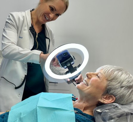 woman smiling while looking at a mirror in a dental room