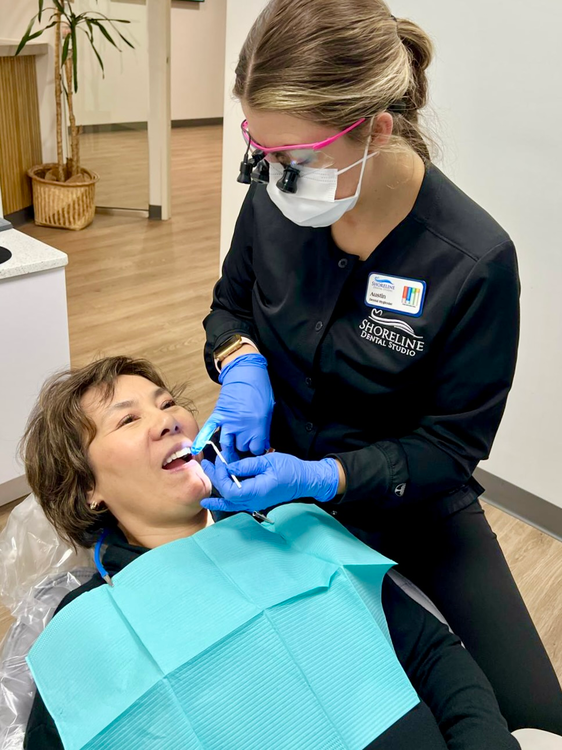 woman in a dental chair getting her teeth brushed by a dentist