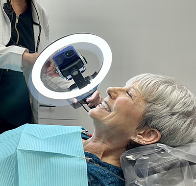 smiling woman in a dental chair with a mirror and a light