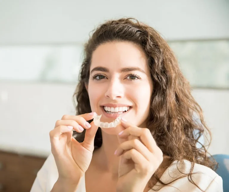 smiling woman holding a toothbrush and a toothpaste in her hand