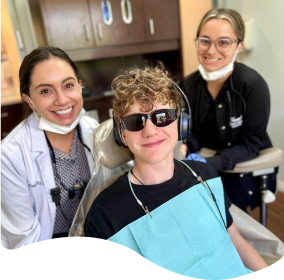 there are two people sitting in a chair with a dentist