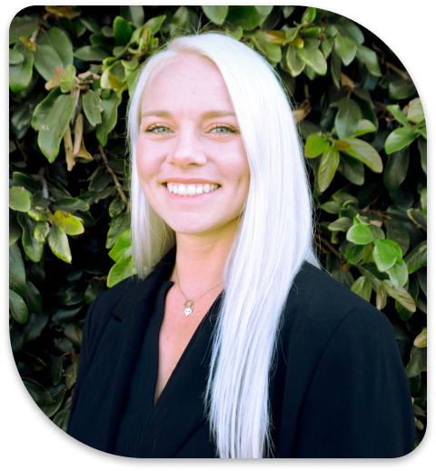 smiling woman with white hair and black shirt in front of a bush