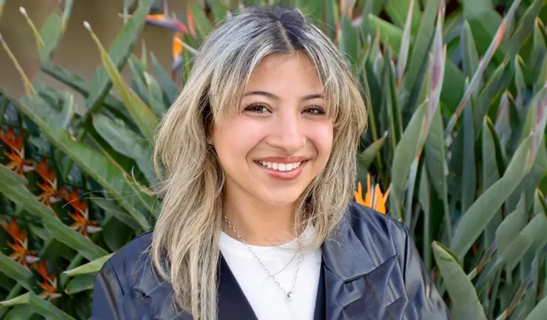 smiling woman with long blonde hair and a black jacket