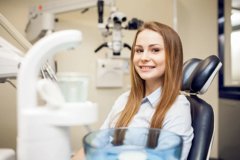 smiling woman sitting in a dental chair with a bowl of water