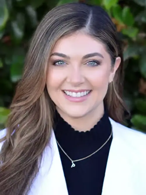 a woman with long hair and a white jacket smiles at the camera