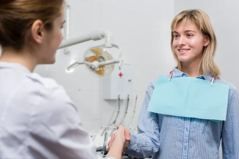 woman in blue shirt shaking hands with a dentist in a room