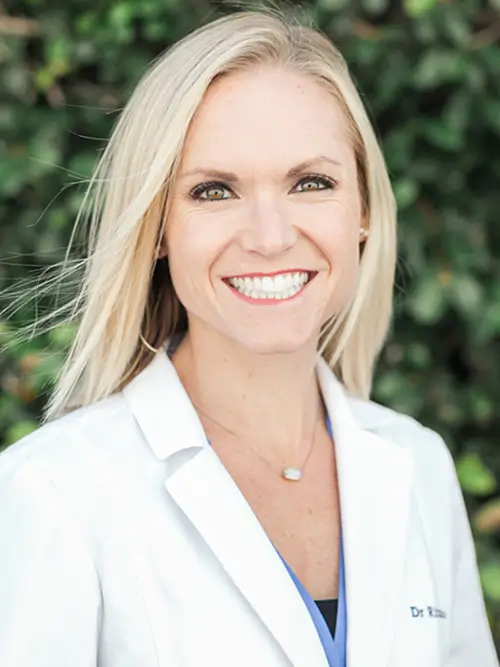 a woman in a white lab coat smiling for a photo