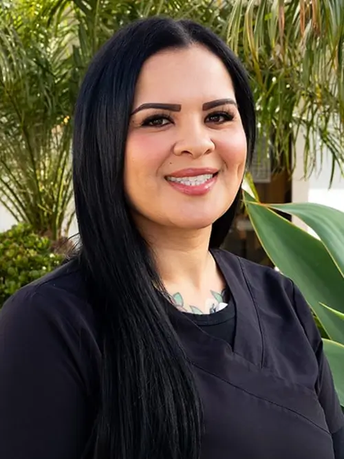 a woman with long black hair and a necklace smiles at the camera