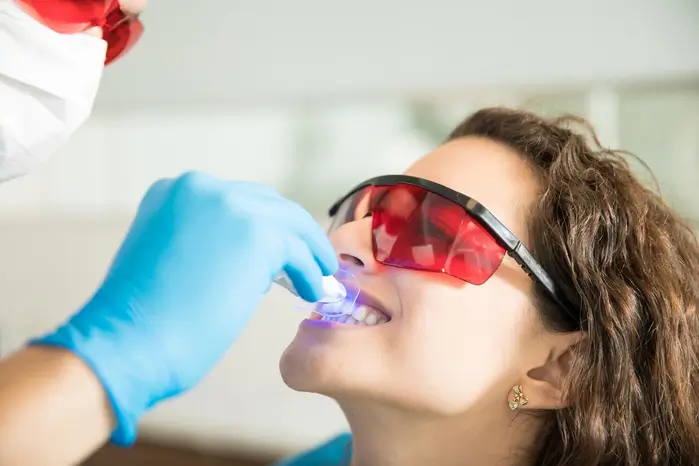 a woman getting her teeth brushed by a dentist